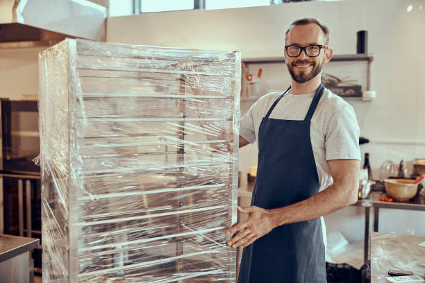 istock Cheerful male worker standing by showcase in cafe 1358842840