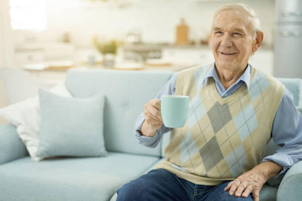 istock Happy old man resting on sofa with cup of tea 1358844082