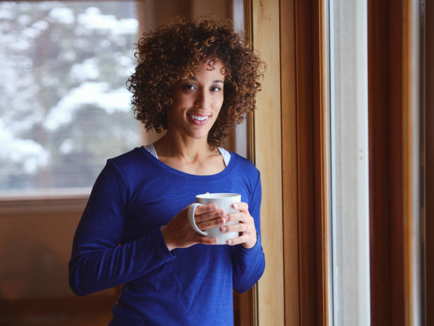 istock Woman in a Home Standing by a Window in Winter 1358844310