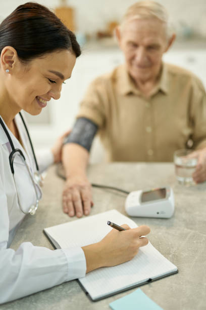 istock Joyful doctor visiting aged man at home and taking notes 1358844749