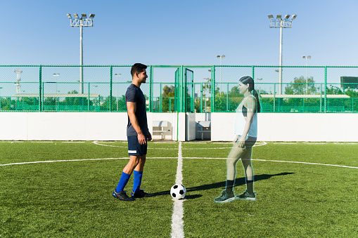 Augmented reality. Active young man connected to the metaverse playing soccer and exercising with a virtual woman