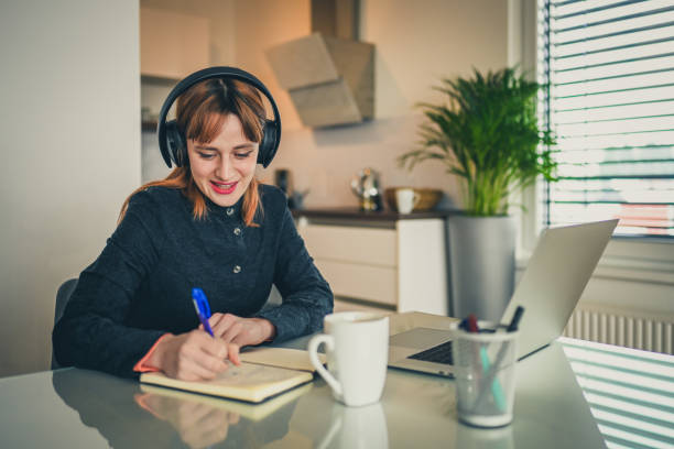 istock Young woman taking notes while listening to lecture on a laptop 1358851904