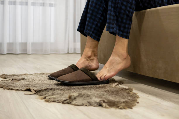 istock Faceless man sits on sofa and puts on slippers. Warm feet 1358854336