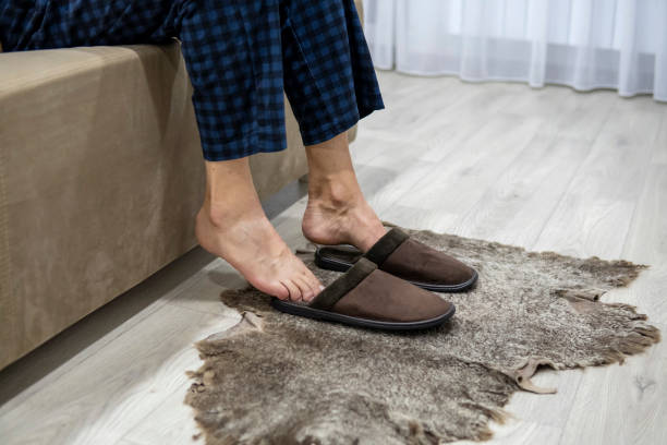 istock Faceless man sits on sofa and puts on slippers. Warm feet 1358854419