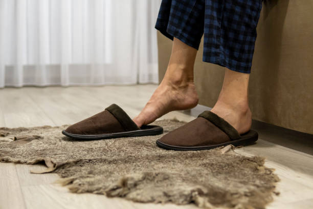 istock Faceless man sits on sofa and puts on slippers. Warm feet 1358854454
