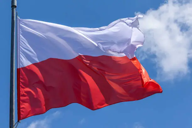 Polish national flag waving on blue sky background. Republic of Poland, PL