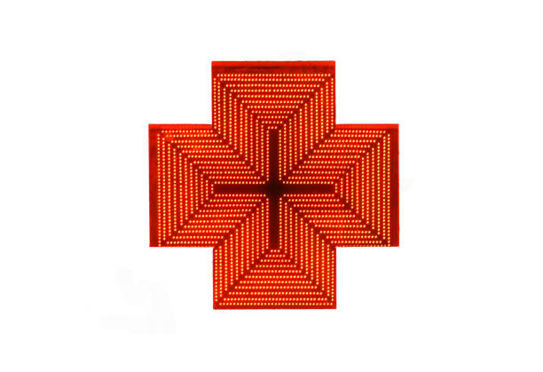 Isolated shining red cross, traditional signboard of a pharmacy. Sale of medicines