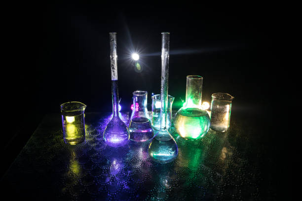 istock Test glass flask with solution in research laboratory. Science and medical background. Laboratory test tubes on dark toned background , science research equipment concept 1358858714