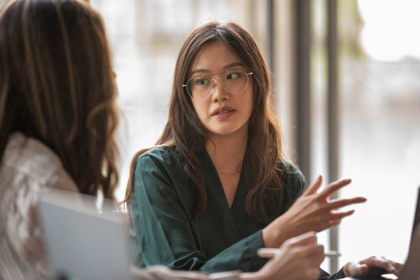 istock Two Asian ladies having a discussion in the office with laptops 1358859656