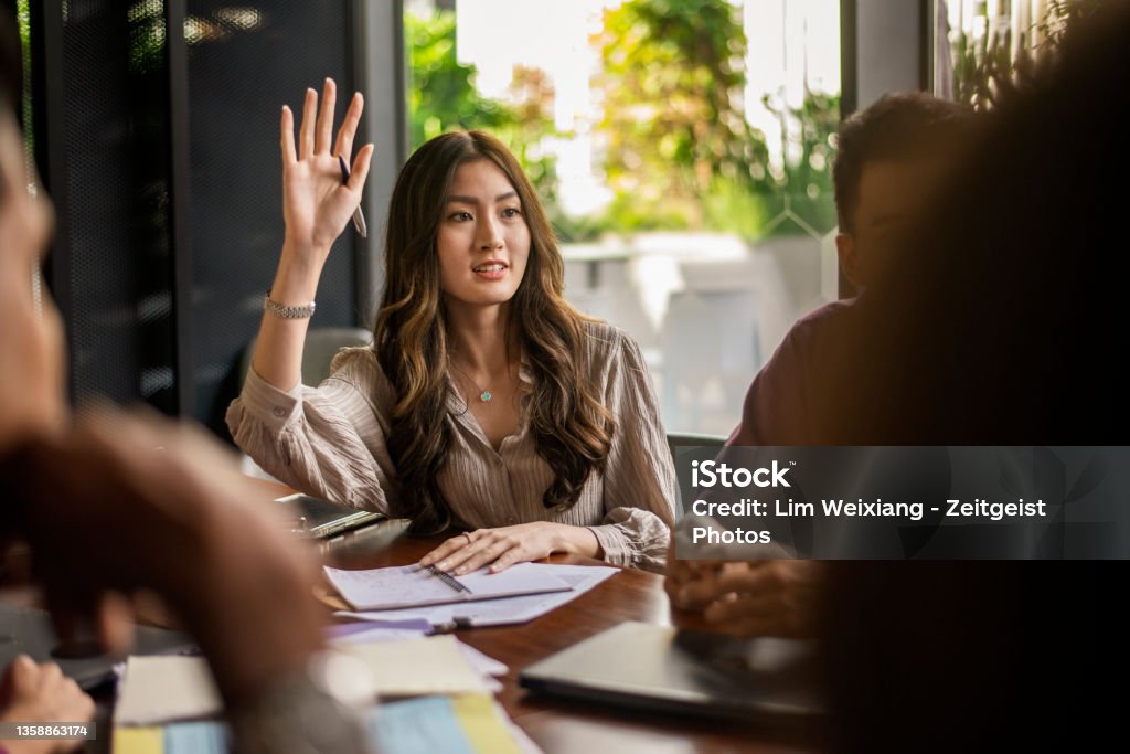 Business lady asking a question during a discussion Business lady raising hand and asking a question during a discussion Asking Stock Photo