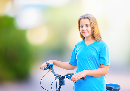 Portrait of teenage girl with bike in park outdoor