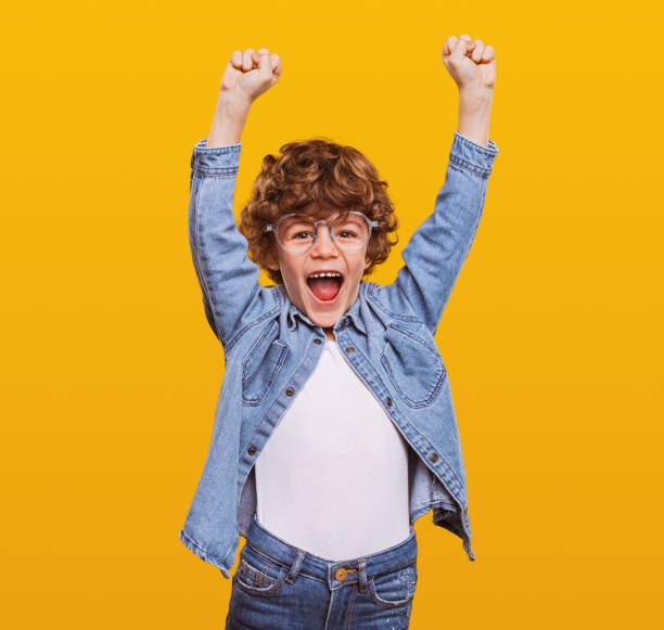 menino encantado celebrando a vitória em estúdio - child excitement awe fun - fotografias e filmes do acervo