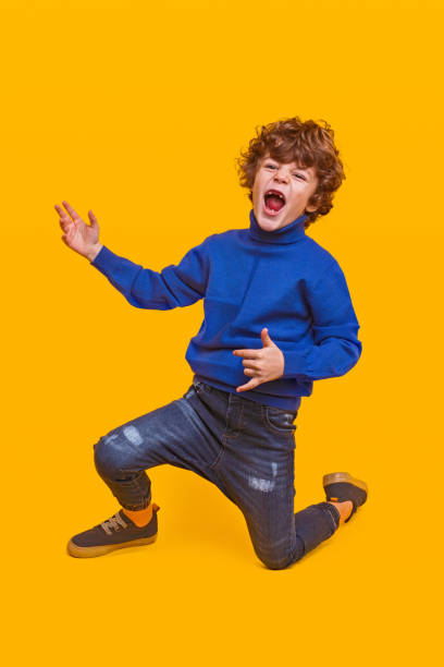 istock Excited little boy having fun on yellow background 1358868221