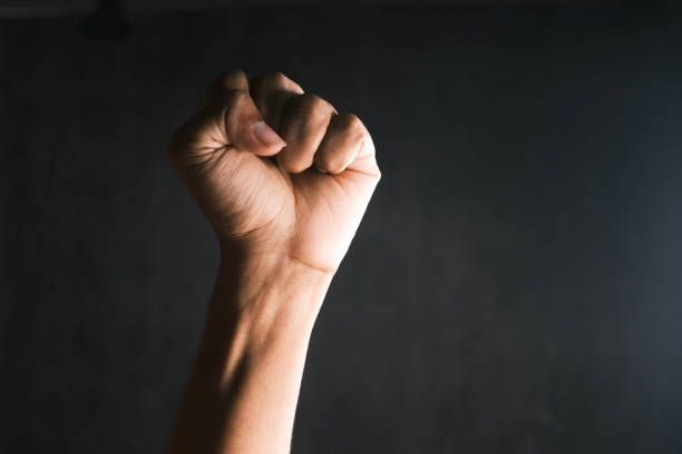 istock hands clenched power strength isolated on black , 1358875968