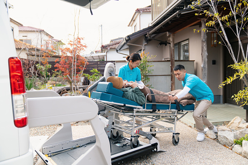 Carers loading a patient into a care taxi. Okayama, Japan.