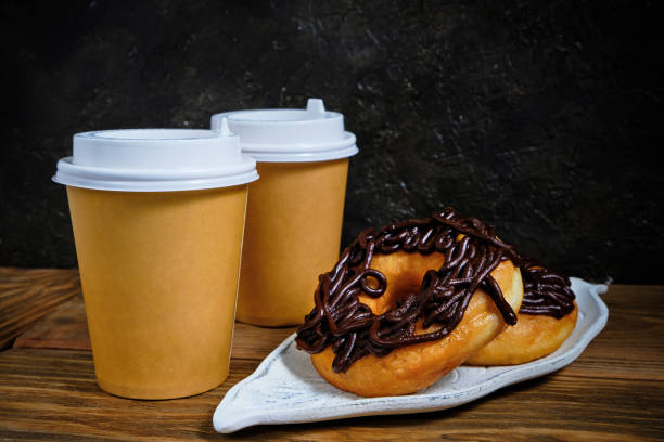 istock Chocolate doughnuts and takeaway coffee on a dark background. 1358889447