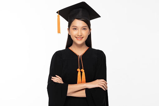 Closeup on happy young female asian graduate student with diploma isolated on grey background.