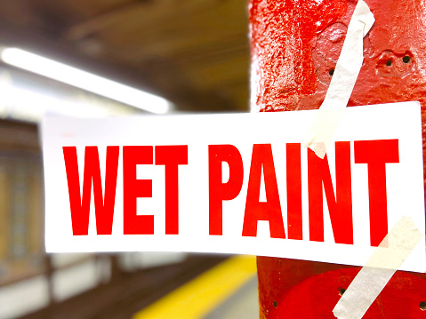 Wet paint sign taped to a red pole.