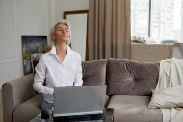 Businesswoman meditating during work from home in living room stock photo