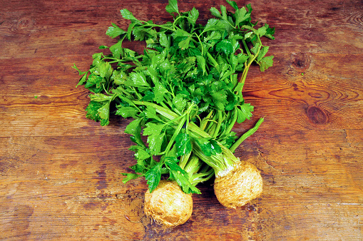 Fresh organic celery with roots on wooden table