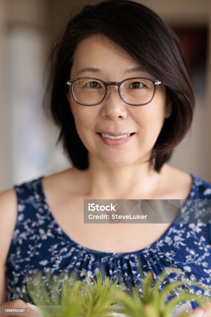 Smiling Asian woman with tray of plants Smiling Japanese woman looking at a tray of plants.. Air Plant Stock Photo