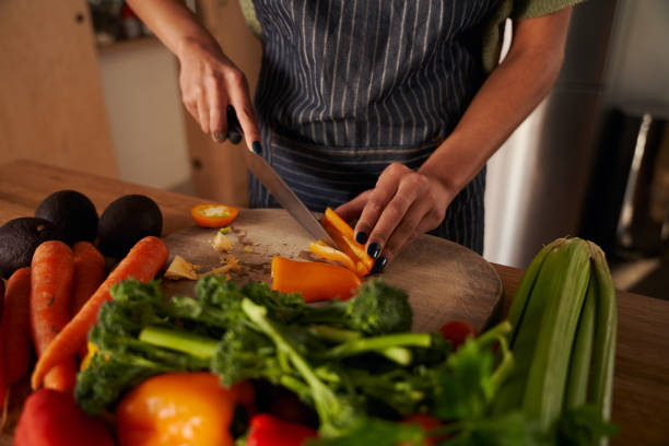 mujer afroamericana cocinando en la cocina picando verduras frescas - ewan fotografías e imágenes de stock