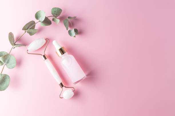 istock Face massage roller with serum or essential oil bottle on pink background. Flat lay, top view, copy space. Facial skin care, body treatment concept. 1358904305