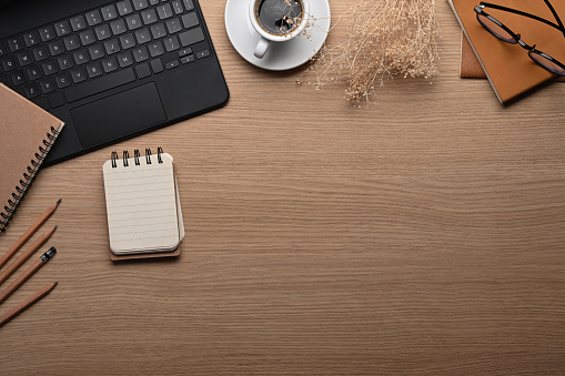 Elegante espacio de trabajo con ordenador portátil, bloc de notas y taza de café sobre mesa de madera. photo