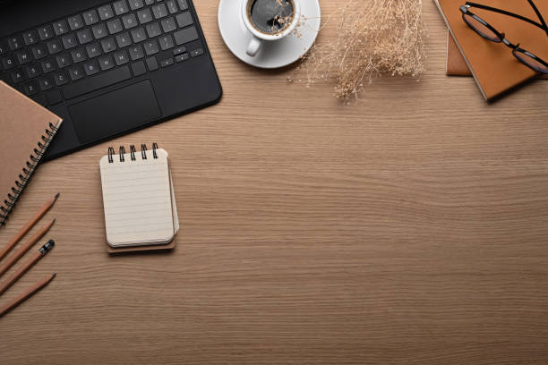 espace de travail élégant avec ordinateur portable, bloc-notes et tasse à café sur une table en bois. - secrétaire photos et images de collection