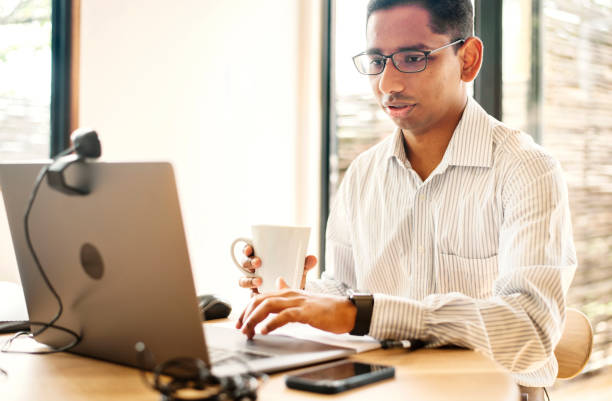 istock Young businessman with a coffee working on a laptop at home 1358905174