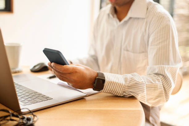 istock Businessman texting on his phone while working on a laptop at a table 1358905216