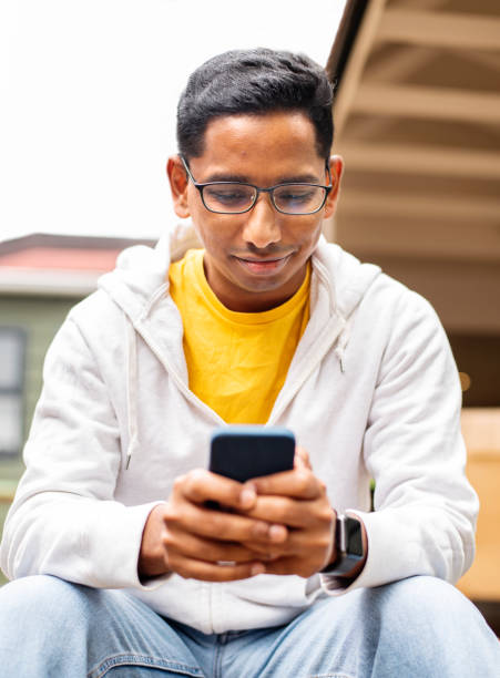 istock Young man texting on his phone while sitting outside on his patio 1358905478
