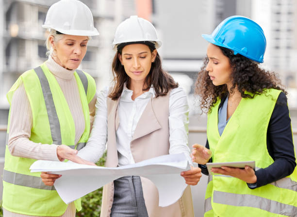 istock Cropped shot of three attractive female engineers looking at blueprints while standing on a construction site 1358906459
