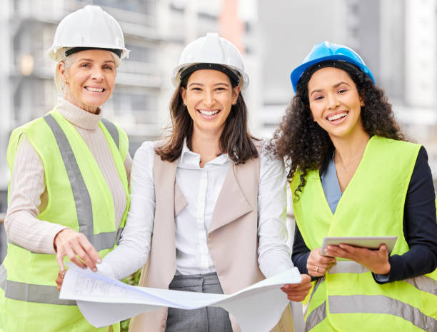 istock Cropped portrait of three attractive female engineers looking at blueprints while standing on a construction site 1358906490