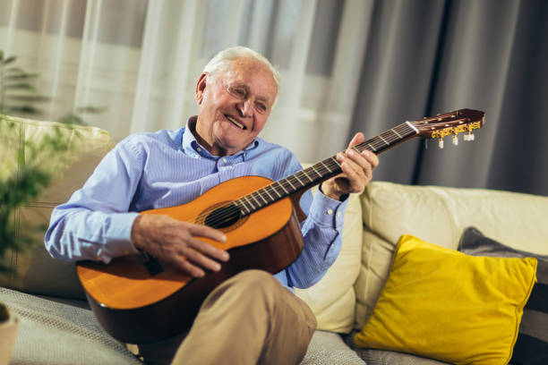 istock Senior man playing guitar at home 1358907782