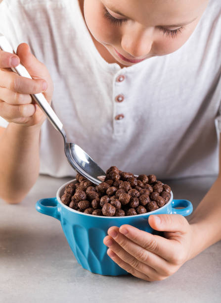 istock Happy boy eats healthy dry breakfast with milk sitting at table in kitchen 1358907995