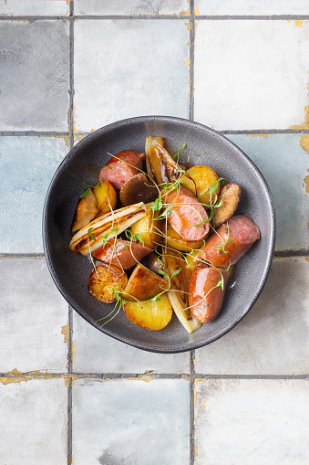 Grilled sausages with potatoes and herbs on a tile background. Meat. Top view. High quality photo