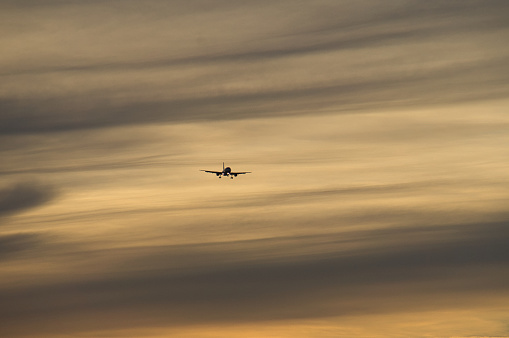 airplane in the evening sky in luminous horizon. vacation trip or cargo transport.