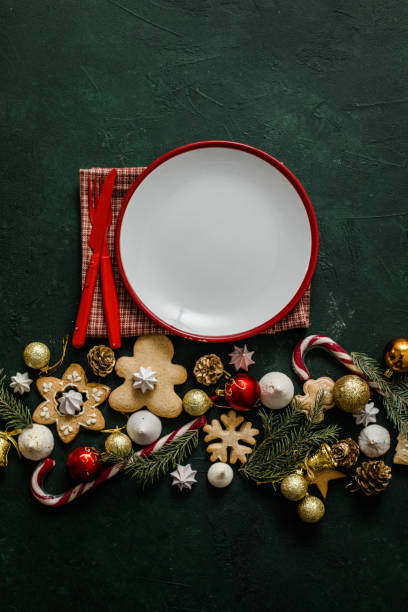 istock Christmas and New year setting table. White empty plate with cutlery and Christmas tree branches, red napkin on a red concrete background. 1358918811