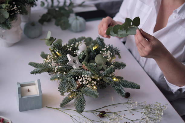 istock Woman decorated a Christmas table decoration. Hands close-up. Master class on making decorative ornaments. Christmas decor with their own hands. Flower shop. Christmas composition of fir branches 1358921369