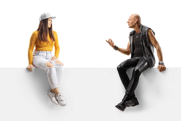 istock Punk talking to a female teenager while sitting on a blank panel 1358921609