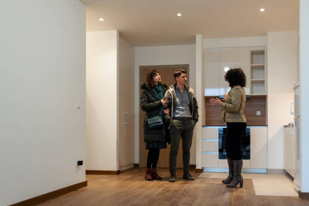 istock Real Estate Agent Welcoming Clients On Front Door 1358922070