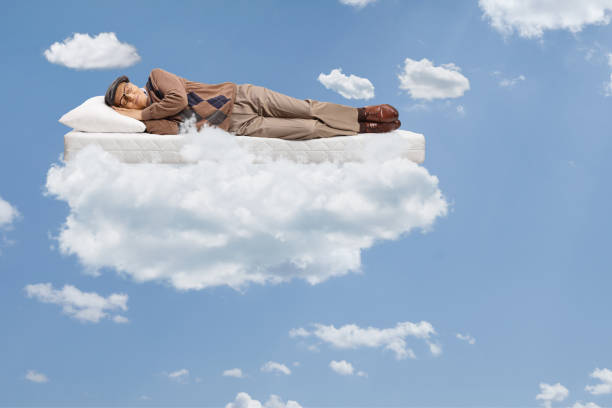 istock Elderly man sleeping on a matress and floating in a blue sky 1358923205