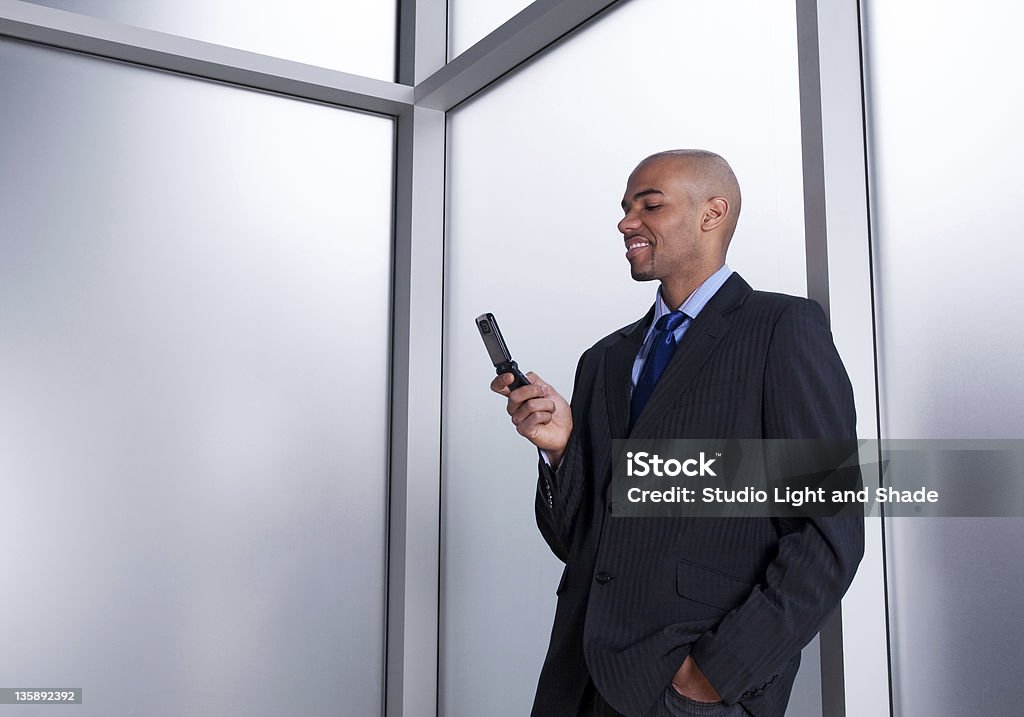 Biznesmen obok okno, patrząc na telefon komórkowy - Zbiór zdjęć royalty-free (20-29 lat)