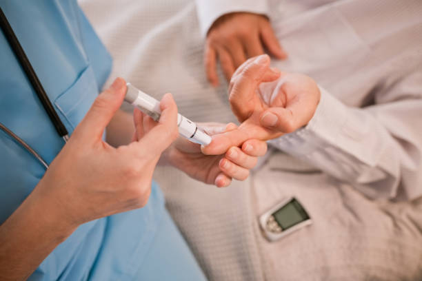 Female caregiver checking diabetes of senior man Female nurse checking diabetes of elderly man through glaucometer. Healthcare worker is examining blood sugar level of senior male. Unrecognizable people. old man pajamas photos stock pictures, royalty-free photos & images