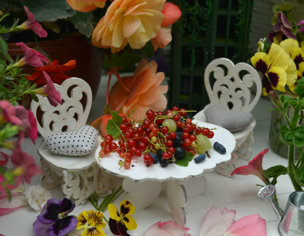 pequeña mesa adorable y sillas para la fiesta del té con flores y bayas.  hadas en el jardín. - alice in wonderland fairy tale tea party old fashioned fotografías e imágenes de stock