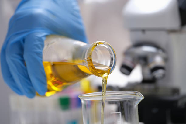 A hand in a glove pours a yellow liquid in the laboratory A hand in a glove pours a yellow liquid in the laboratory, close-up, blurry. Optical microscope, urine analysis beaker pour stock pictures, royalty-free photos & images