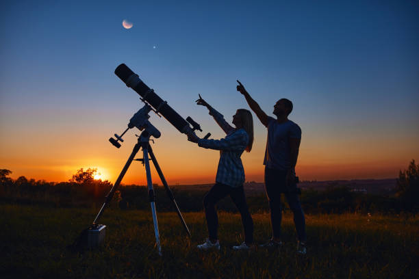 istock Couple stargazing together with a astronomical telescope. 1358927763