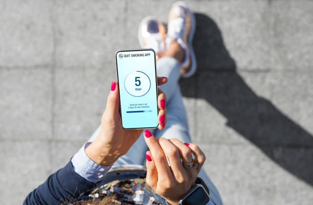 istock Woman holding mobile phone outdoors and using app to help quit smoking 1358931263