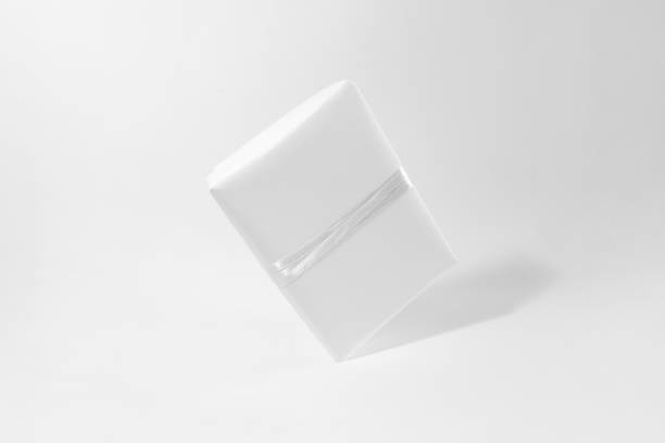 istock One gift box in white wrapping paper with white rope on white table. Isolated wrapped gift mock up with ribbon. 1358935039